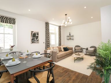 A living room with a dining table set for four a sofa two armchairs and a coffee table at Alice House Stone Cross Mansion in Ulverston