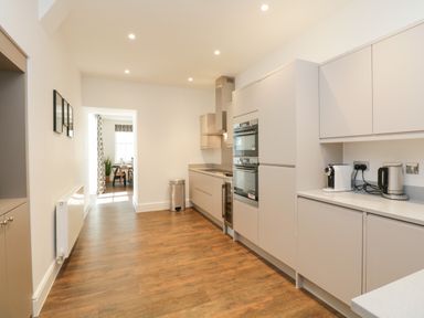 A kitchen with wooden floor cabinets appliances and a dining area visible at Alice House Stone Cross Mansion in Ulverston
