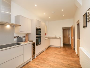 A kitchen with built-in ovens sink and cabinetry and wooden flooring at Alice House Stone Cross Mansion in Ulverston