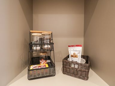Two wicker baskets on a kitchen counter one with jars and snacks the other with a bag of pet treats at Alice House Stone Cross Mansion in Ulverston