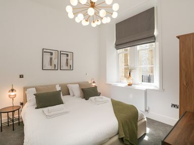 A bedroom with a double bed side tables lamps and a window with blinds at Alice House Stone Cross Mansion in Ulverston