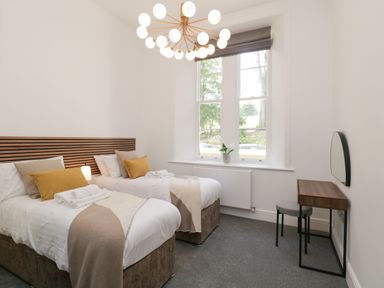 A bedroom with two single beds a window a desk and a chair at Alice House Stone Cross Mansion in Ulverston