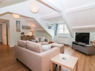 A living room with sofa and TV at Smugglers Loft in Looe