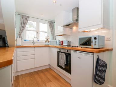 A kitchen with appliances and wooden worktop at Smugglers Loft in Looe