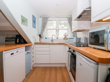 A kitchen with cabinets and appliances at Smugglers Loft in Looe
