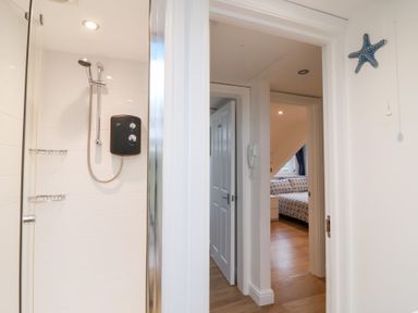 A bathroom with a shower and adjacent bedroom door at Smugglers Loft in Looe