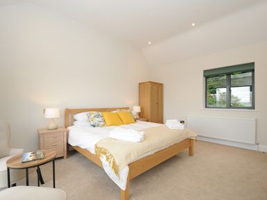 A bedroom with a double bed bedside tables lamps a wardrobe and a window at Sandsgate Lodge in Spinster's Rock near Chagford