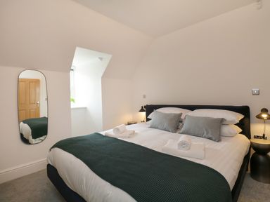 A bedroom with a double bed pillows and towels next to a window and a wall mirror at William Tower Suite Stone Cross Mansion in Ulverston
