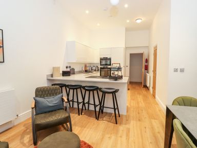 A kitchen with stools at a counter and chairs in a sitting area at William Tower Suite Stone Cross Mansion in Ulverston