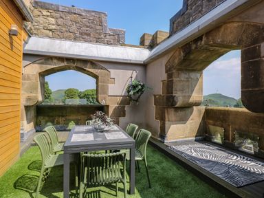 An outdoor dining area with a table and six chairs on artificial grass at William Tower Suite Stone Cross Mansion in Ulverston