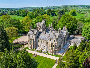 A large stone mansion surrounded by trees and grassland at The Elizabeth Suite Stone Cross Mansion in Ulverston