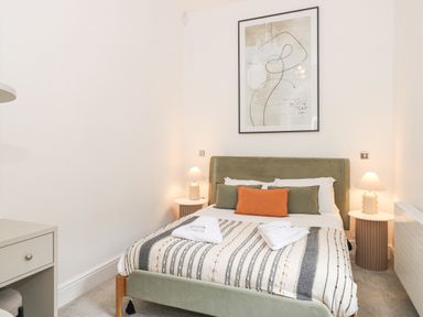 A bedroom with a bed with folded towels on a striped blanket two bedside tables with lamps at The Elizabeth Suite Stone Cross Mansion in Ulverston