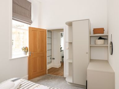 A bedroom corner with a wooden door a window with a plant a wardrobe shelves and a small desk at The Elizabeth Suite Stone Cross Mansion in Ulverston