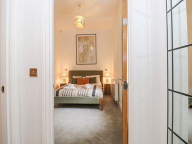 A bedroom with a bed lamps bedside tables and a framed painting at The Elizabeth Suite Stone Cross Mansion in Ulverston