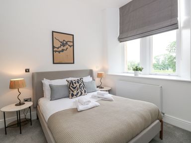 A bedroom with a bed lamps and a window with a plant on the sill at The Elizabeth Suite Stone Cross Mansion in Ulverston