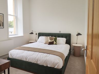 A bedroom with a bed a window and bedside tables with lamps at The Alfred Suite Stone Cross Mansion in Ulverston