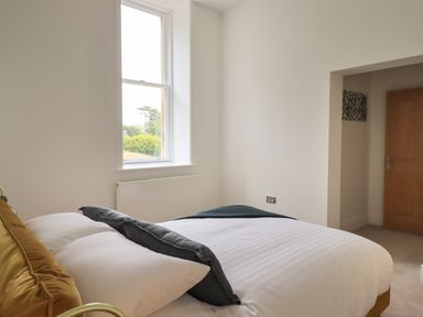 A bedroom with a bed white bedding pillows and a window at The Alfred Suite Stone Cross Mansion in Ulverston