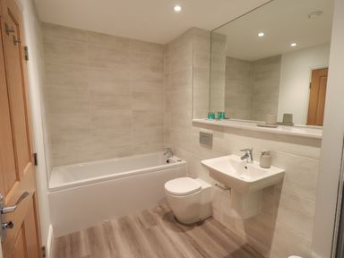 A bathroom with a bathtub a toilet a sink a large mirror and toiletries at The Alfred Suite Stone Cross Mansion in Ulverston