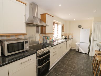 A kitchen with appliances including microwave stove refrigerator and stools at The Wheat House in Welford-On-Avon