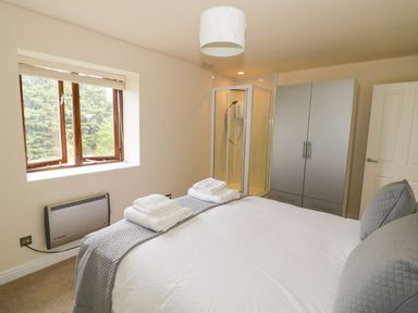A bedroom with a bed towels a shower cubicle wardrobe and a window at The Wheat House in Welford-On-Avon