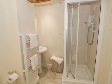 A bathroom with a shower enclosure a sink a towel rack with towels and a toilet paper holder at The Wheat House in Welford-On-Avon