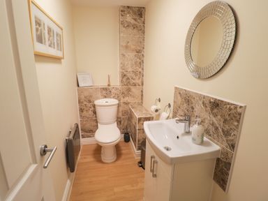 A small bathroom with a toilet sink and round mirror at The Wheat House in Welford-On-Avon