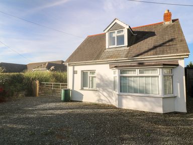 A white detached house with a gabled roof and gravel driveway at Alpha in St Minver