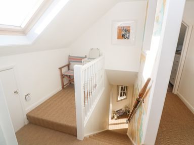 A stairwell with a wooden chair and a handrail with a map on the wall at Alpha in St Minver