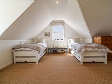 A bedroom with two single beds a small table and a wooden chest of drawers at Alpha in St Minver
