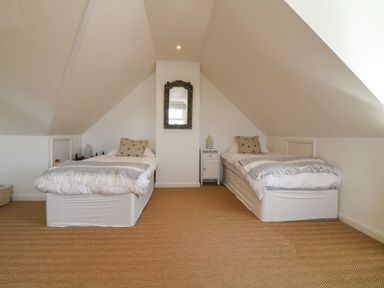 A bedroom with two single beds and a mirror on the wall at Alpha in St Minver