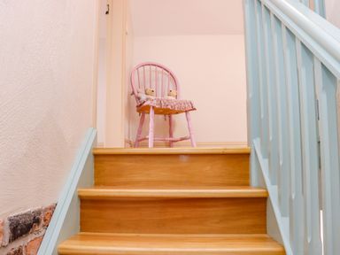 Wooden stairs with blue railing and a pink chair with stuffed animals at Cob Cottage in Kilmore County Wexford