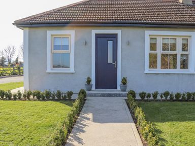 A front view of a house with a blue door two windows and a garden path at An Teachain in Adamstown County Wexford
