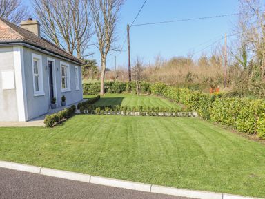 A front yard with trimmed grass and small hedges next to a house at An Teachain in Adamstown County Wexford