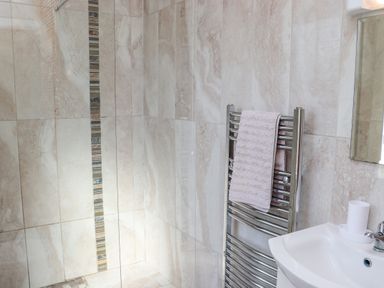 A tiled bathroom with a towel on a heated rack and a sink with a soap holder at An Teachain in Adamstown County Wexford