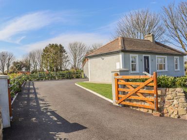 A driveway leading to a house with a wooden gate and stone wall at An Teachain in Adamstown County Wexford