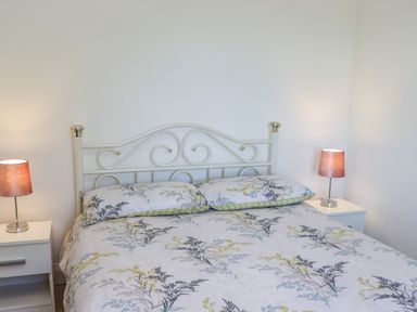 A bedroom with a double bed with patterned bedding and two bedside tables with lamps at An Teachain in Adamstown County Wexford