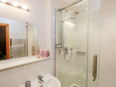 A bathroom with a shower enclosure sink a mirror and a towel radiator at Rothay in Ambleside