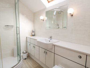 A bathroom with a shower enclosure sink and cabinets at Rothay in Ambleside