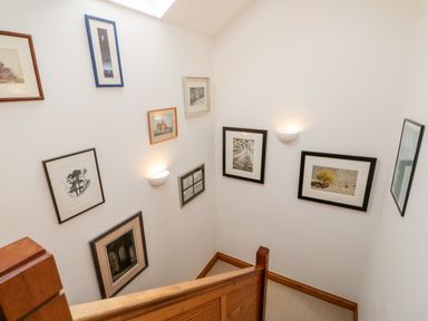 A staircase with framed pictures on the walls and wall-mounted lights at Rothay in Ambleside