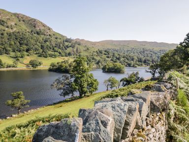 A stone wall with a lake and trees on a hillside at Rothay in Ambleside