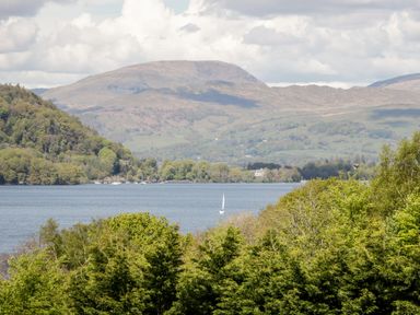 A lake with a sailboat surrounded by trees and hills at Rothay in Ambleside