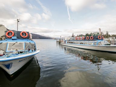 Two boats docked on a lake with hills and clouds in the background at Rothay in Ambleside