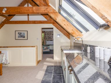 A kitchen area with a sink countertop under skylight windows and a view into a bedroom at The Coach House at Thorn Farm Bridford near Moretonhampstead