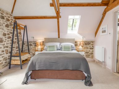 A bedroom with a bed lamps and open closet rack at The Coach House at Thorn Farm Bridford near Moretonhampstead