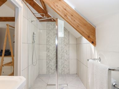 A bathroom with a walk-in shower and wooden beams at The Coach House at Thorn Farm in Bridford near Moretonhampstead