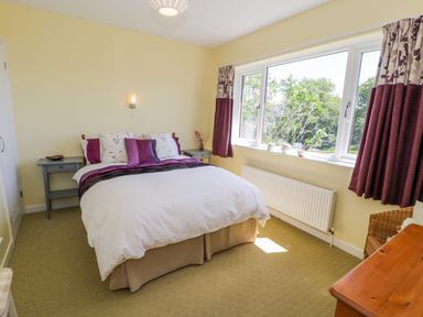 A bedroom with a double bed and purple curtains at Ceris in Penrhyndeudraeth