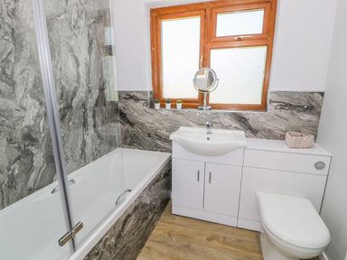 A bathroom with a bathtub shower combination sink vanity and toilet at Ceris in Penrhyndeudraeth