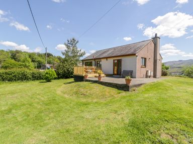 A house with a grass lawn and potted plants on a patio at Ceris in Penrhyndeudraeth
