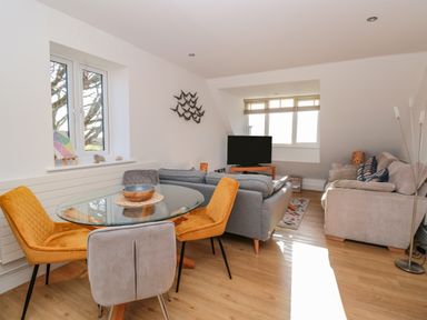 A living room with sofas a glass dining table with chairs and a television at Seaspray Stoke Fleming Near Dartmouth