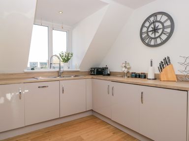 A kitchen with cabinets a sink a toaster and a knife set at Seaspray Stoke Fleming Near Dartmouth